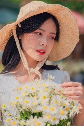 亚洲戴草帽手捧小雏菊花束的美女图片